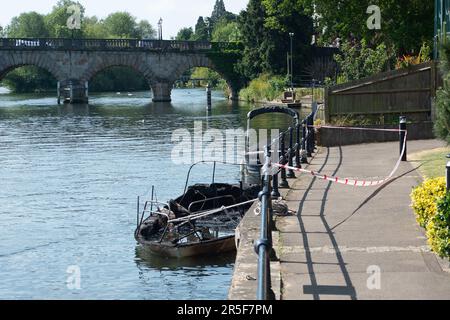 Maidenhead, UK. 3rd June, 2023. Two boats have been destroyed by fire in two separate incidents this week during the early hours of 31st May and 2nd June along the River Thames in Maidenhead, Berkshire. One of the charred wrecks remains cordoned off (pictured) and is now moored outside the riverside Chandlers Quay flats where there is a strong smell of fuel. The other boat that was destroyed by fire near to Boulter's Lock has, according to local residents, now sunk. Fortunately nobody was injured in the two fires. Thames Valley Police are reported to be making further investigations into alleg Stock Photo