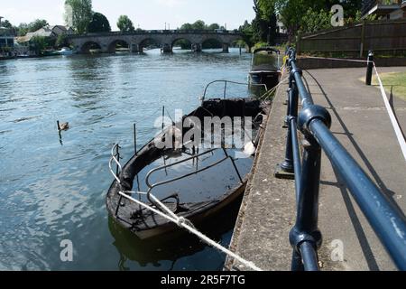 Maidenhead, UK. 3rd June, 2023. Two boats have been destroyed by fire in two separate incidents this week during the early hours of 31st May and 2nd June along the River Thames in Maidenhead, Berkshire. One of the charred wrecks remains cordoned off (pictured) and is now moored outside the riverside Chandlers Quay flats where there is a strong smell of fuel. The other boat that was destroyed by fire near to Boulter's Lock has, according to local residents, now sunk. Fortunately nobody was injured in the two fires. Thames Valley Police are reported to be making further investigations into alleg Stock Photo