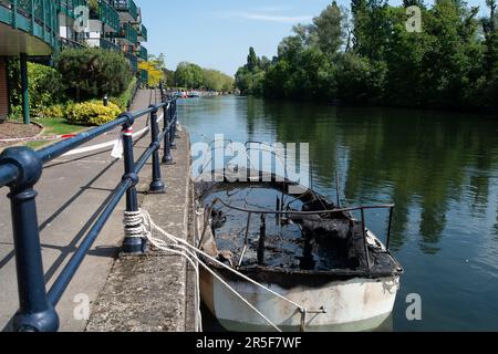 Maidenhead, UK. 3rd June, 2023. Two boats have been destroyed by fire in two separate incidents this week during the early hours of 31st May and 2nd June along the River Thames in Maidenhead, Berkshire. One of the charred wrecks remains cordoned off (pictured) and is now moored outside the riverside Chandlers Quay flats where there is a strong smell of fuel. The other boat that was destroyed by fire near to Boulter's Lock has, according to local residents, now sunk. Fortunately nobody was injured in the two fires. Thames Valley Police are reported to be making further investigations into alleg Stock Photo