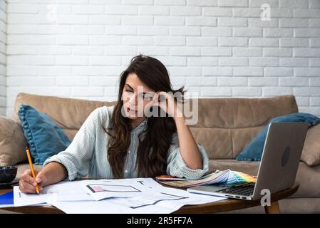 Woman architect working on interior renovation in workplace. Designer choosing color samples according to the visualization and blueprints of the proj Stock Photo
