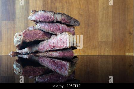 "Savor the essence of a perfectly sliced, grilled beef steak, beautifully captured against a rustic wooden backdrop—a feast for the senses. Stock Photo