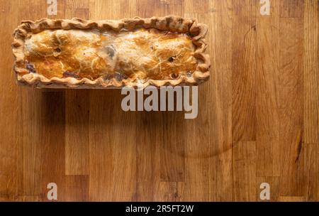 Delicious Chicken Ham and Egg Pie displayed on a rustic wooden board, perfect for slicing and serving. Stock Photo
