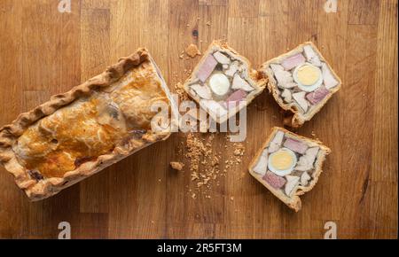 Savoury Chicken Ham and Egg Pie showcased with three mouth-watering slices on a wooden chopping board. Stock Photo