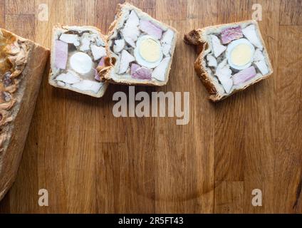 Close-up view of three delectable slices of Chicken Ham and Egg Pie arranged beautifully on a wooden board. Stock Photo