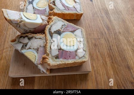 A delectable portion of Chicken Ham and Egg Pie showcasing the appetising combination of cooked meat and boiled egg. Stock Photo