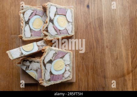 Tempting Chicken Ham and Egg Pie presented with nice slices on a small wooden board, ready to be enjoyed. Stock Photo