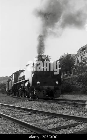 Hr1 class passenger express steam locomotive 1009 pulling a train in Eira, Helsinki, before this part of the Helsinki harbour rail line was dismantled in the 1990s. Merikatu buildings in the background. Stock Photo