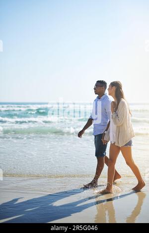 The sweethearts are enjoying themselves. a young couple taking a stroll along the beach. Stock Photo