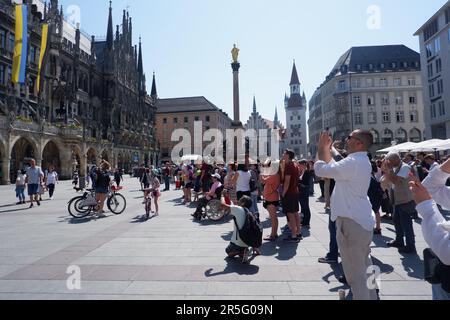 Crowds of spectators watch the chiming of the Rathaus Glockenspiel Carillon at Munich Rathus (Town Hall) in in Marienplatz Square Stock Photo