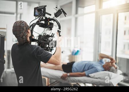 Just another day on set. Behind the scenes shot of a camera operator shooting a scene with a state of the art camera inside of a studio during the day Stock Photo