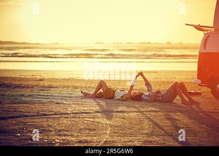 Theres something about your touch...an affectionate young couple holding hands while lying on the beach. Stock Photo