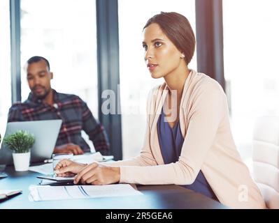 Creative ambition at its best. a young woman using a digital tablet during a meeting with her colleagues in the background. Stock Photo