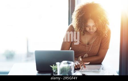 The smart worker is a connected worker. a young woman using a digital tablet at her work desk. Stock Photo
