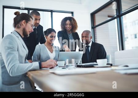 Using a online survey tool to better their customer service. a group of businesspeople discussing something on a laptop. Stock Photo