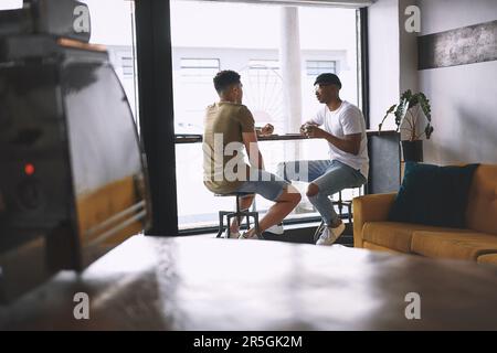 You had me at Lets go for coffee. two young men talking while having coffee together in a cafe. Stock Photo