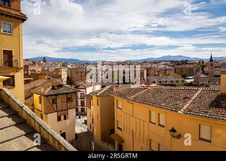 Segovia cityscape with narrow stone streets, medieval architecture and Iglesia de San Martín bell tower, mountains in the background. Stock Photo