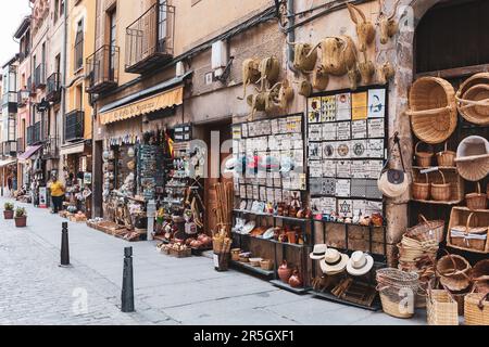 Segovia, Spain, 03.10.21. Souvenir shop display on a narrow medieval street with wicker baskets, hats, decorative tiles, magnets, pottery. Stock Photo