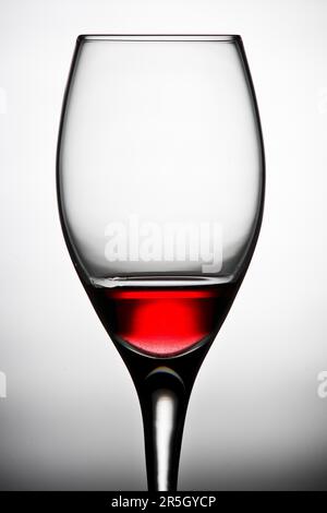 Curved wine glass filled with red wine against a white background Stock Photo