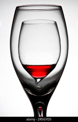 Curved double wine glass filled with red wine against a white background Stock Photo