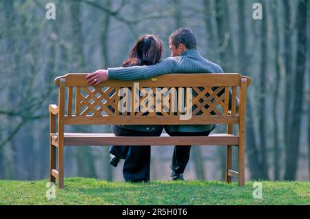 Couple sitting on park bench Stock Photo