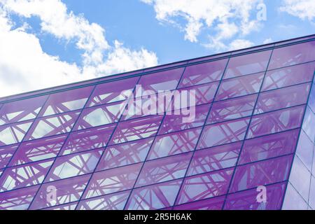 Stylish Glass Facade of Violet Tinted Semi-Transparent Glass Building Against Blue Sky with Sunbeams. Modern Architecture Concept Stock Photo