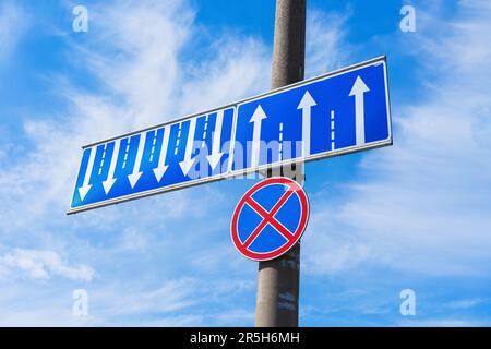 A traffic sign prohibiting car parking (red cross on blue circle) with an additional sign indicating lane distribution (multi-lane traffic) - white ar Stock Photo