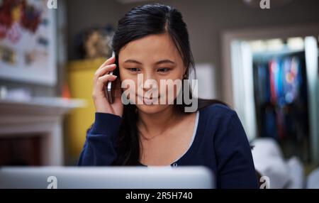 Im reading the report as we speak. an attractive young female entrepreneur making a call while working from home. Stock Photo