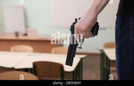 School shooting. Man with gun in classroom, closeup Stock Photo