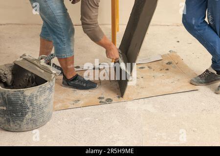Worker spreading adhesive mix over tile with spatula, closeup Stock Photo