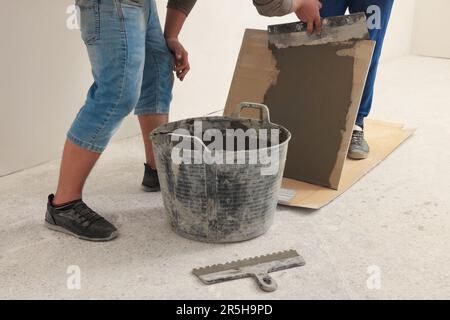 Worker spreading adhesive mix over tile with spatula, closeup Stock Photo