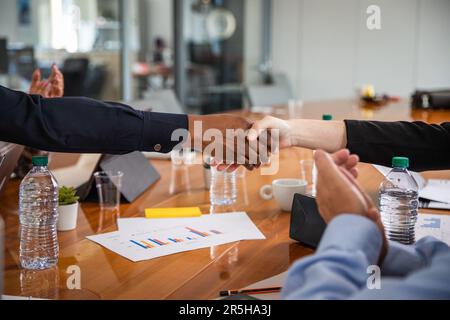 Handshake between two people of different ethnicities during a meeting in a conference room. Stock Photo