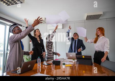 A group of business people celebrate a business achievement by throwing papers in the air Stock Photo