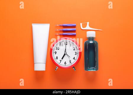 Dental floss, toothpaste and mouthwash on orange background, flat lay Stock Photo