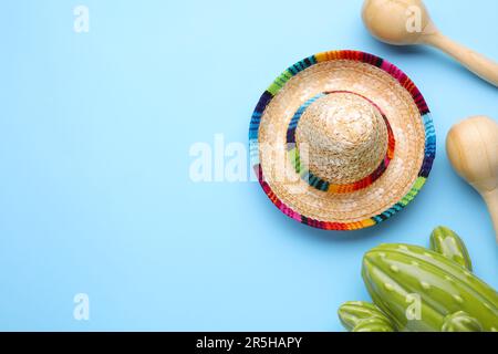 Wooden maracas, toy cactus and sombrero hat on light blue background, flat lay with space for text. Musical instrument Stock Photo