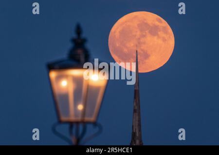 London, UK. 3rd June 2023. UK Weather: Full Strawberry Moon rises over All Saints' Blackheath church. The moon's nickname is often attributed to the time-keeping traditions of various Native American tribes and after wild strawberries ripening this time of the year. Credit: Guy Corbishley/Alamy Live News Stock Photo