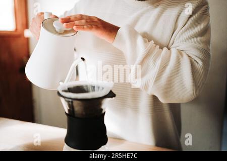 Unrecognizable young man preparing coffee using chemex pour over coffee maker and drip kettle, in a coffee shop Stock Photo