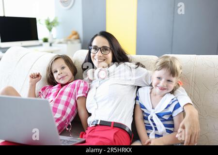 Smiling mother with children on sofa and laptop Stock Photo