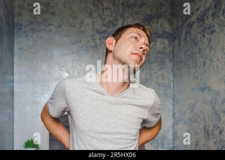 Male with kidney pain. Young Caucasian man suffering from back pain at home. Backache, lumbago concept. Stock Photo