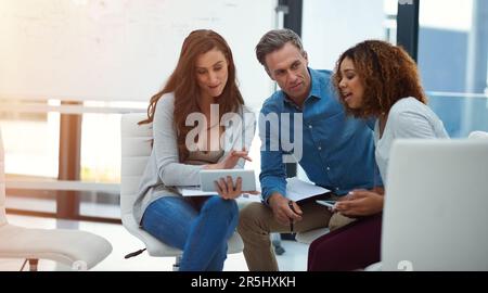 The smartest teams use the smartest technologies. a creative team using a digital tablet together during a meeting at work. Stock Photo