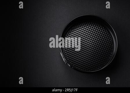 Round metal black detachable baking dish for baking on a dark concrete background Stock Photo