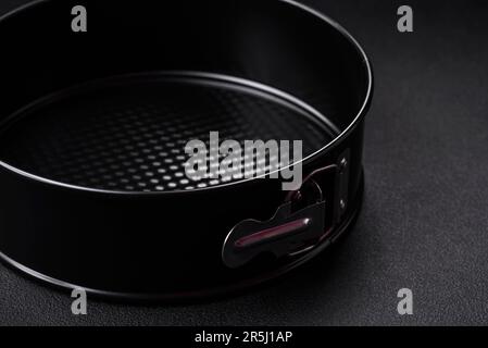 Round metal black detachable baking dish for baking on a dark concrete background Stock Photo