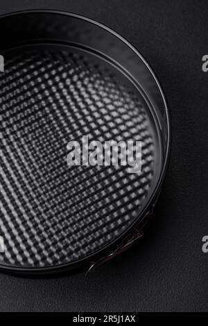 Round metal black detachable baking dish for baking on a dark concrete background Stock Photo
