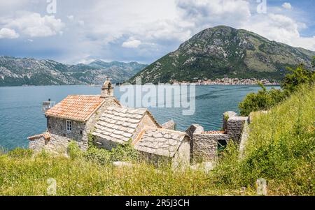 Our Lady of Angels or the Lepetani Orthodox Church seen protecting Perast in the distance in the Bay of Kotor in June 2023. Stock Photo