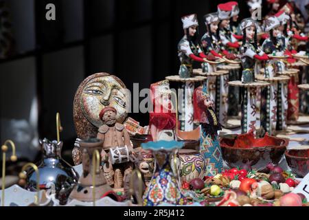 A beautifully painted clay mosaic pot in woman face shape in the background, doll in traditional Armenian outfit, pots and jugs in clay, at a souvenir Stock Photo