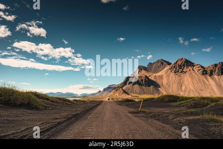 Dramatic landscape of Vestrahorn mountain with dirt road between black sand beach in Stokksnes peninsula at Iceland Stock Photo