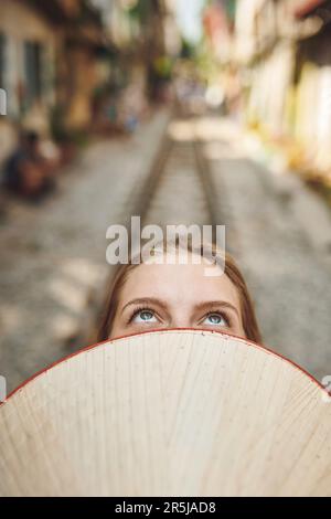 Traveling changed the way I see the world. a woman holding a conical hat in front of her face. Stock Photo