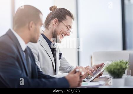 Smart entrepreneurs use smart technology. two young businessmen using a digital tablet together at work. Stock Photo