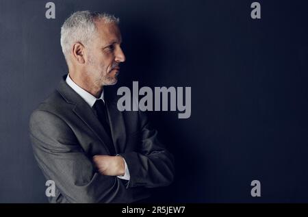 Hes eagle eyed in money matters. Studio shot of a mature businessman against a dark background. Stock Photo