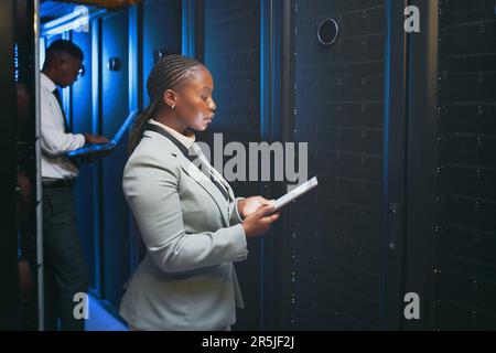 Updating our security system. two young IT specialists standing together in the server room and using technology. Stock Photo