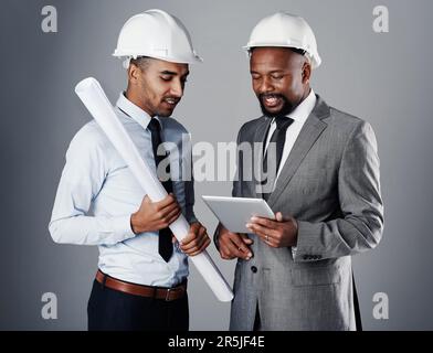 Building the cities of the future. two civil engineers discussing building plans while standing in the studio. Stock Photo